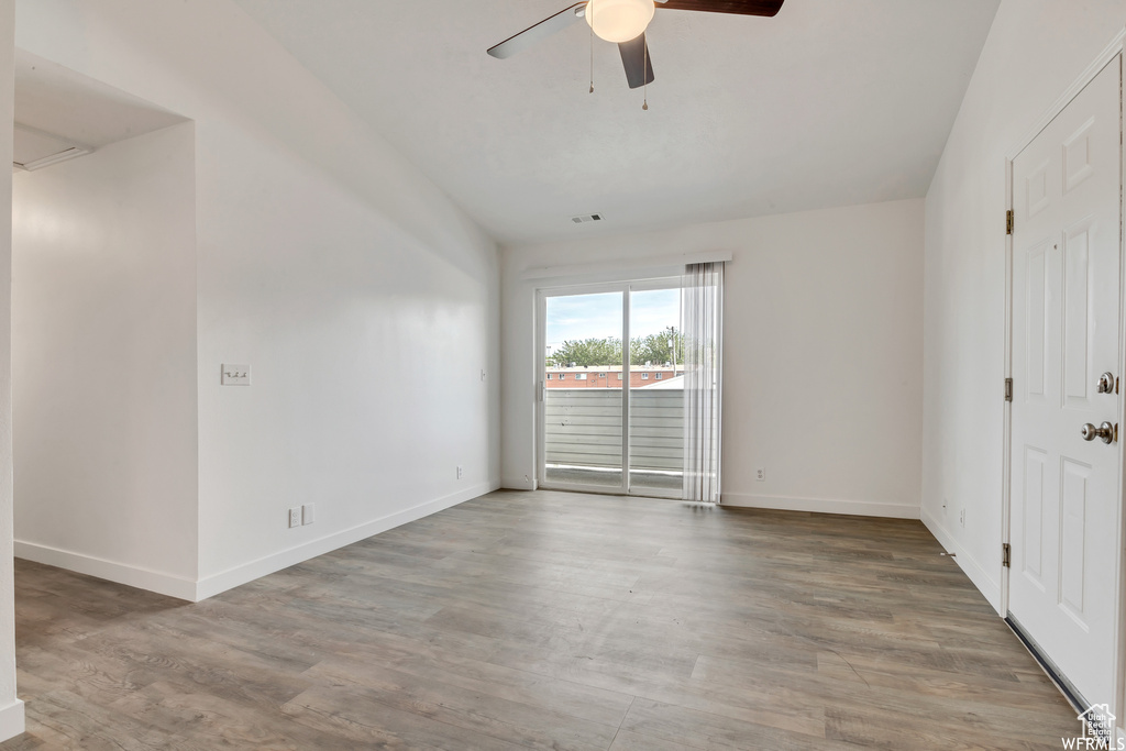Unfurnished room with a ceiling fan, wood finished floors, lofted ceiling, and baseboards