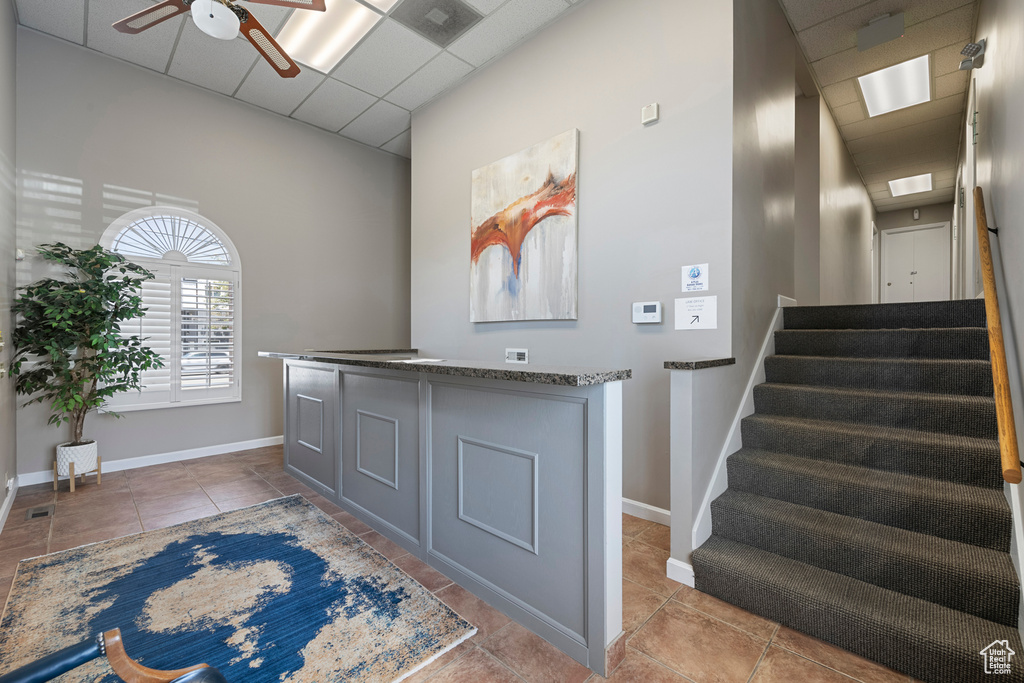 Tiled foyer entrance with a ceiling fan, stairway, baseboards, and a paneled ceiling