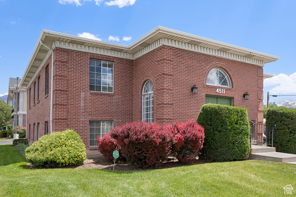 View of property exterior with a lawn and brick siding