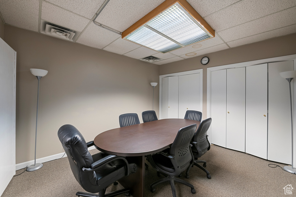 Carpeted office with a drop ceiling and baseboards