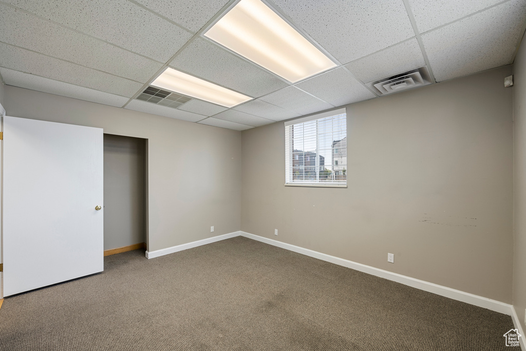 Basement featuring a drop ceiling, carpet floors, and baseboards