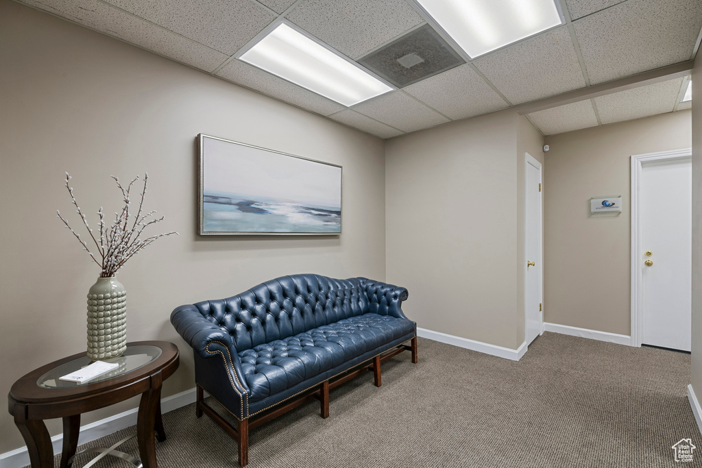 Living area featuring carpet flooring, a paneled ceiling, and baseboards