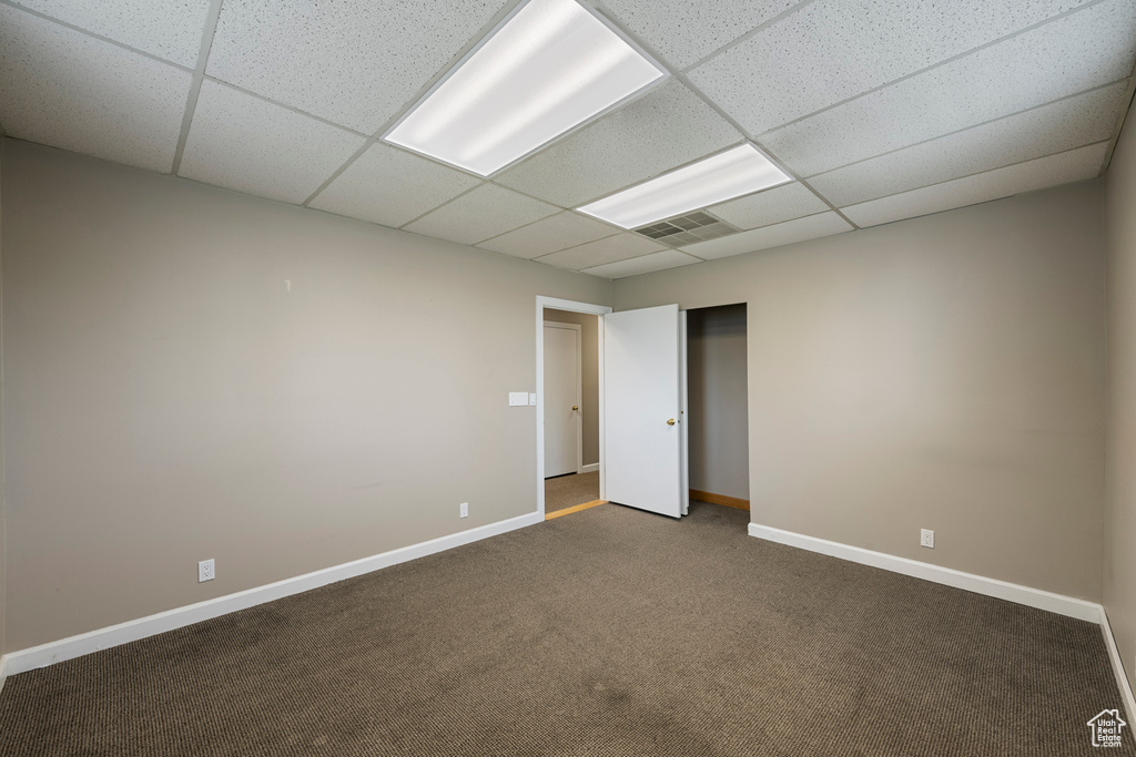 Unfurnished bedroom featuring a paneled ceiling, carpet floors, and baseboards
