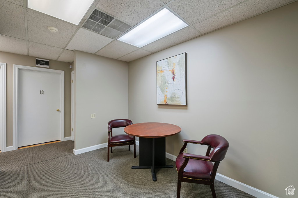 Living area with carpet floors, baseboards, and a paneled ceiling