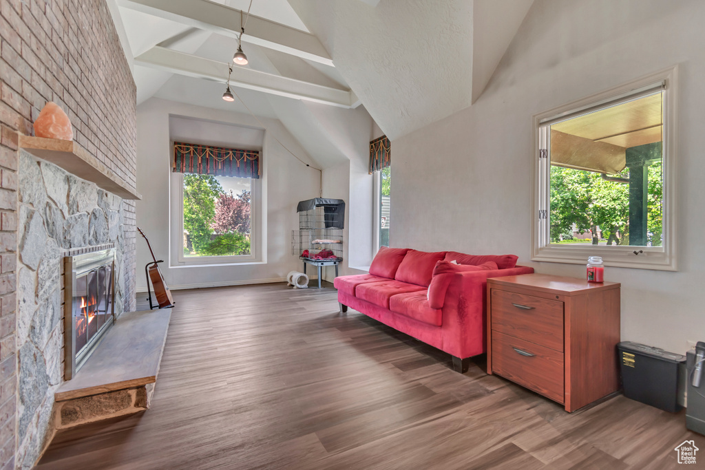Living room with lofted ceiling, wood finished floors, and a stone fireplace