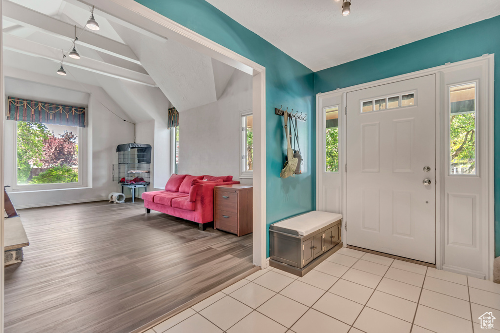 Entryway with track lighting, vaulted ceiling, and light wood-style floors