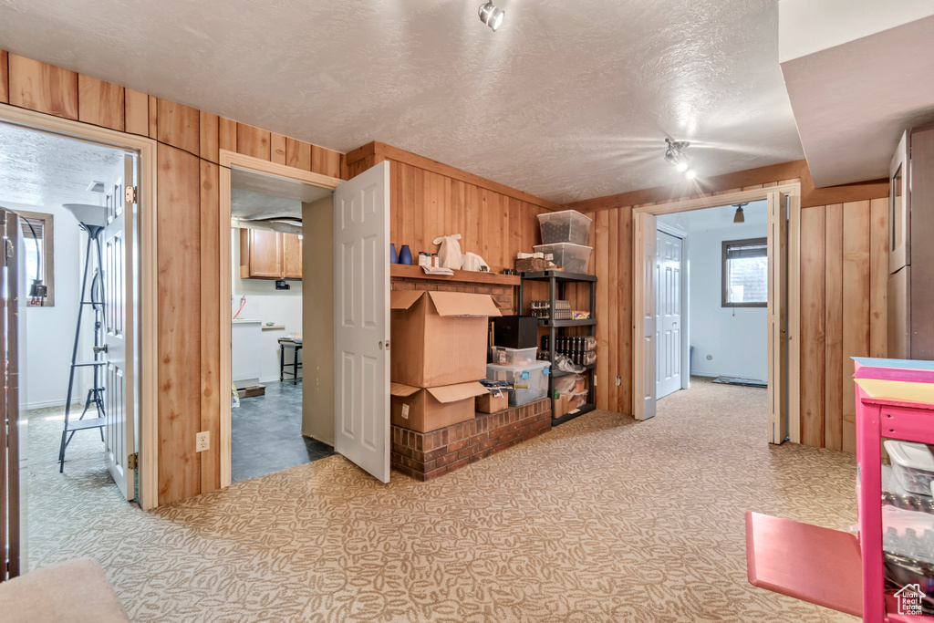 Carpeted bedroom featuring wooden walls and a textured ceiling