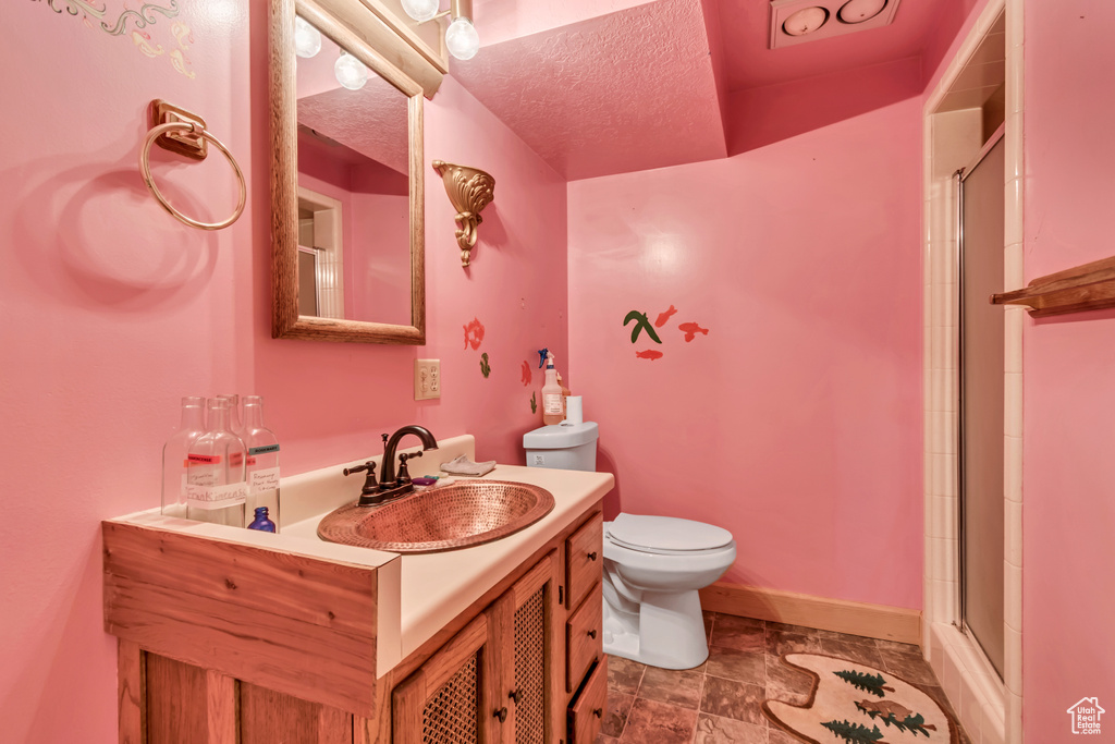 Bathroom with toilet, vanity, a shower with shower door, and baseboards