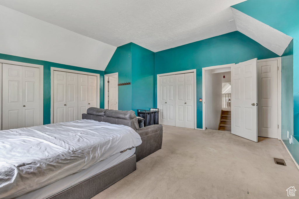 Carpeted bedroom with lofted ceiling and two closets