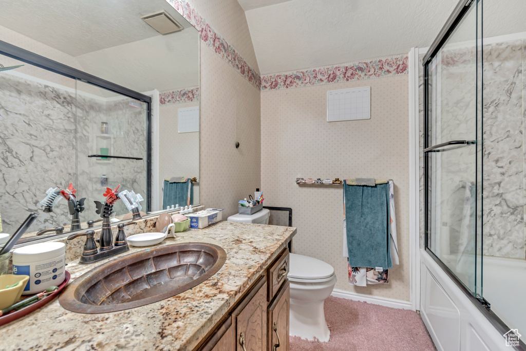 Full bathroom with vanity, toilet, vaulted ceiling, bath / shower combo with glass door, and baseboards