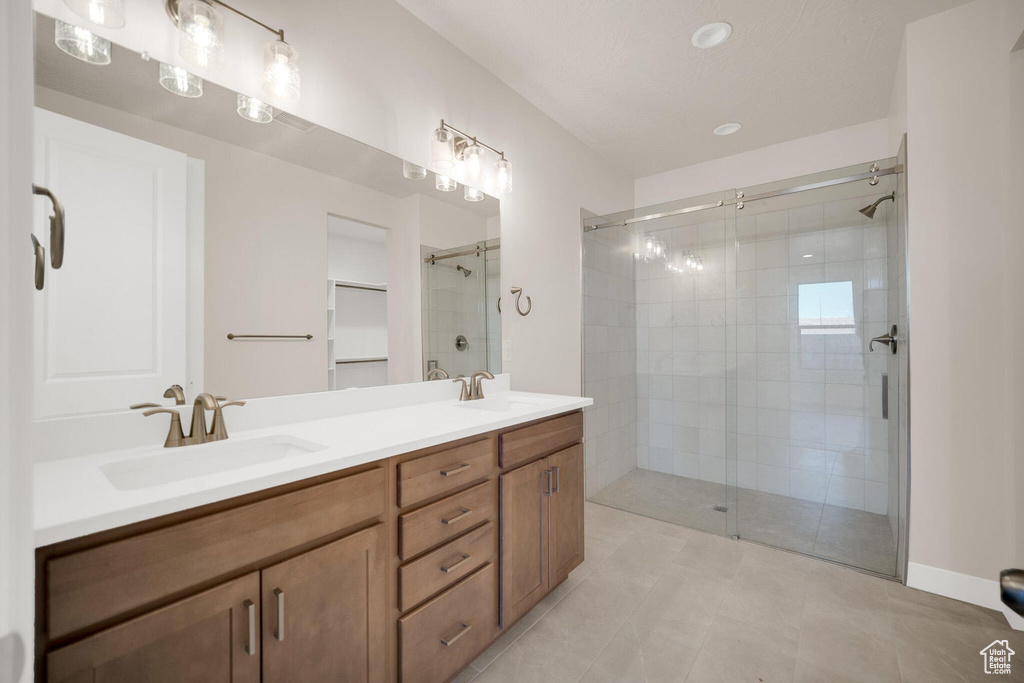 Bathroom with a shower stall, double vanity, and tile patterned floors