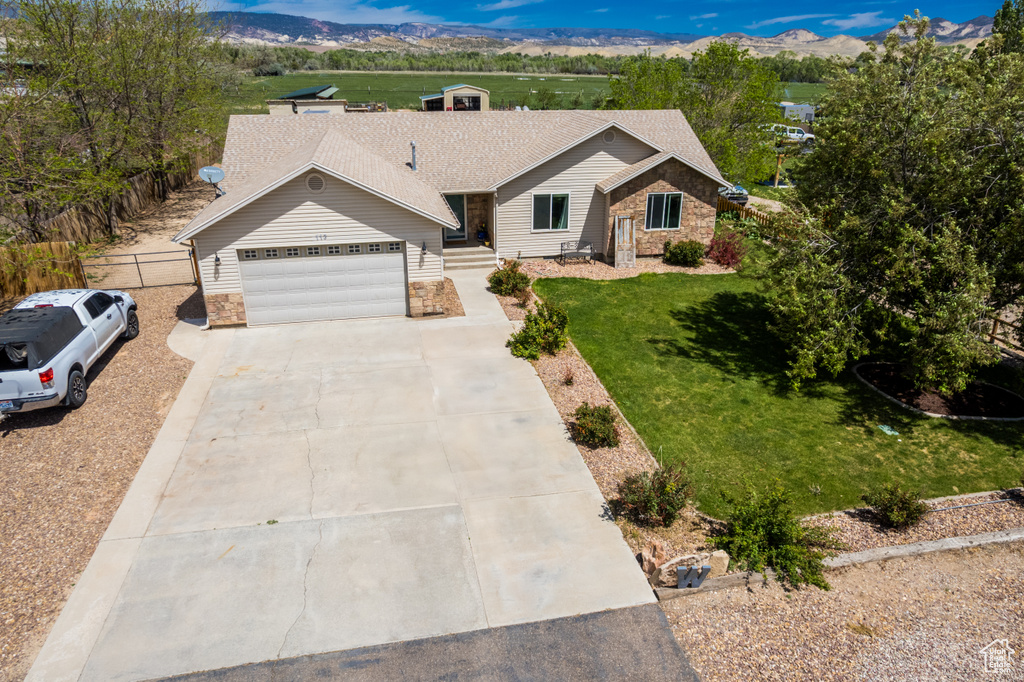 Ranch-style house with stone siding, a garage, a front yard, and driveway
