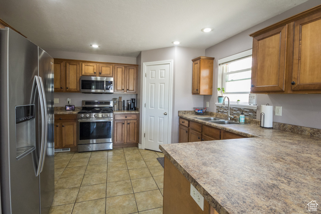 Kitchen featuring stainless steel appliances, brown cabinets, a sink, and recessed lighting