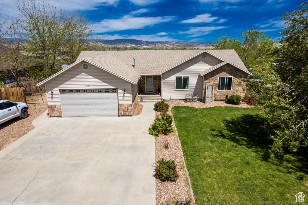 Single story home with stone siding, concrete driveway, a garage, roof with shingles, and a mountain view
