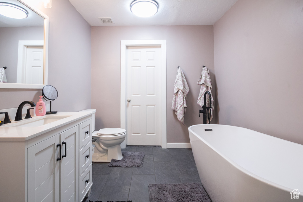 Bathroom featuring a soaking tub, vanity, and toilet