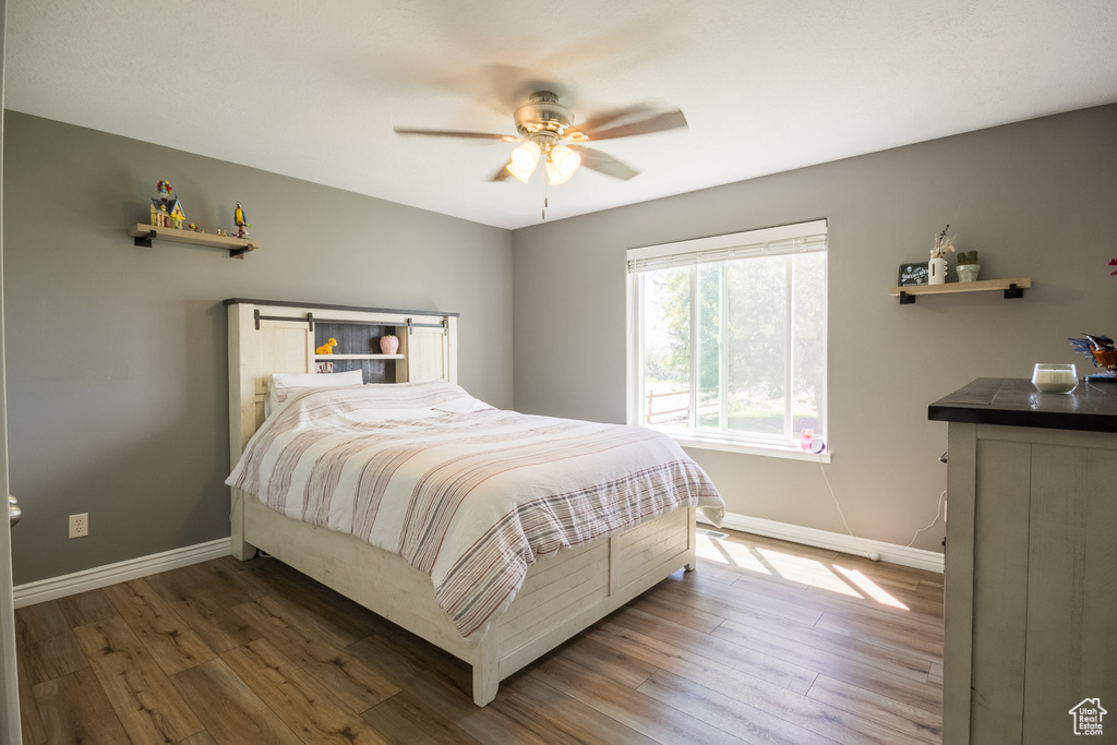 Bedroom with baseboards, wood finished floors, and a ceiling fan