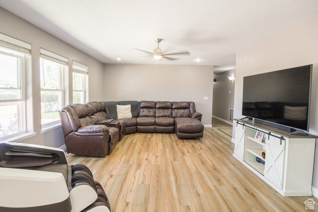 Living area featuring light wood-style floors, ceiling fan, baseboards, and recessed lighting