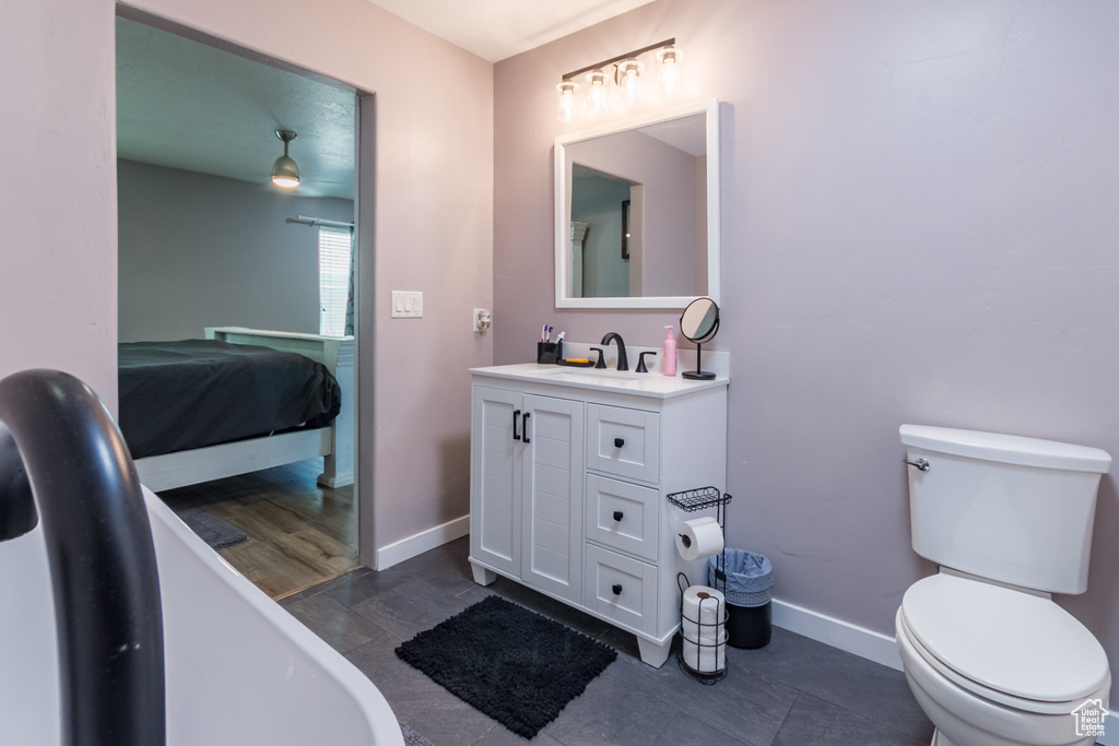 Ensuite bathroom featuring vanity, a freestanding tub, baseboards, toilet, and tile patterned floors