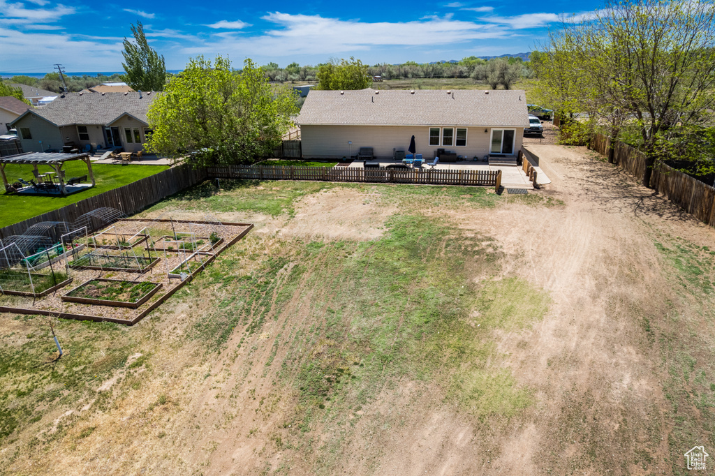 Rear view of house with a vegetable garden, a wooden deck, and dirt driveway