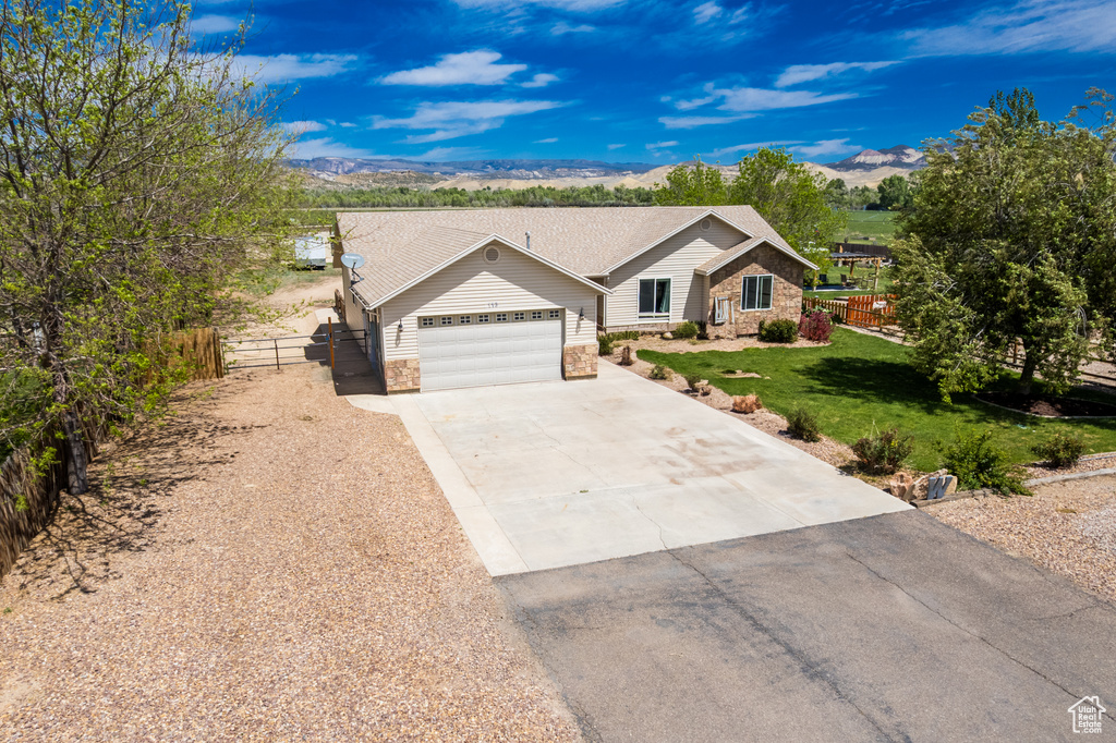 Ranch-style home with stone siding, a garage, concrete driveway, and a mountain view