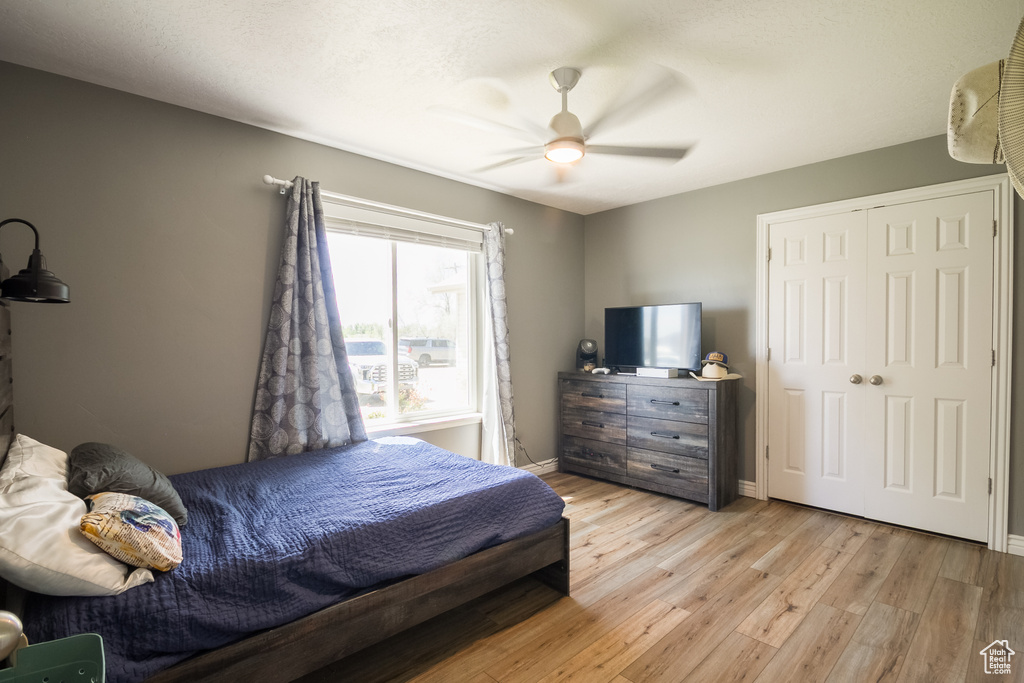 Bedroom featuring light wood-style flooring, a ceiling fan, baseboards, and a closet