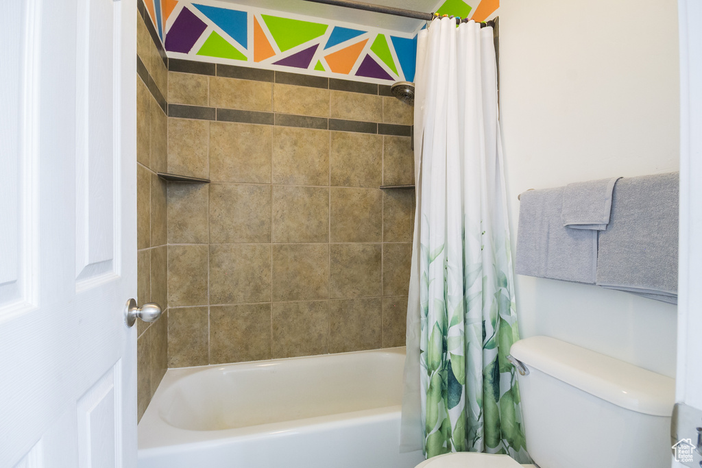 Bathroom with toilet and shower / bath combo with shower curtain