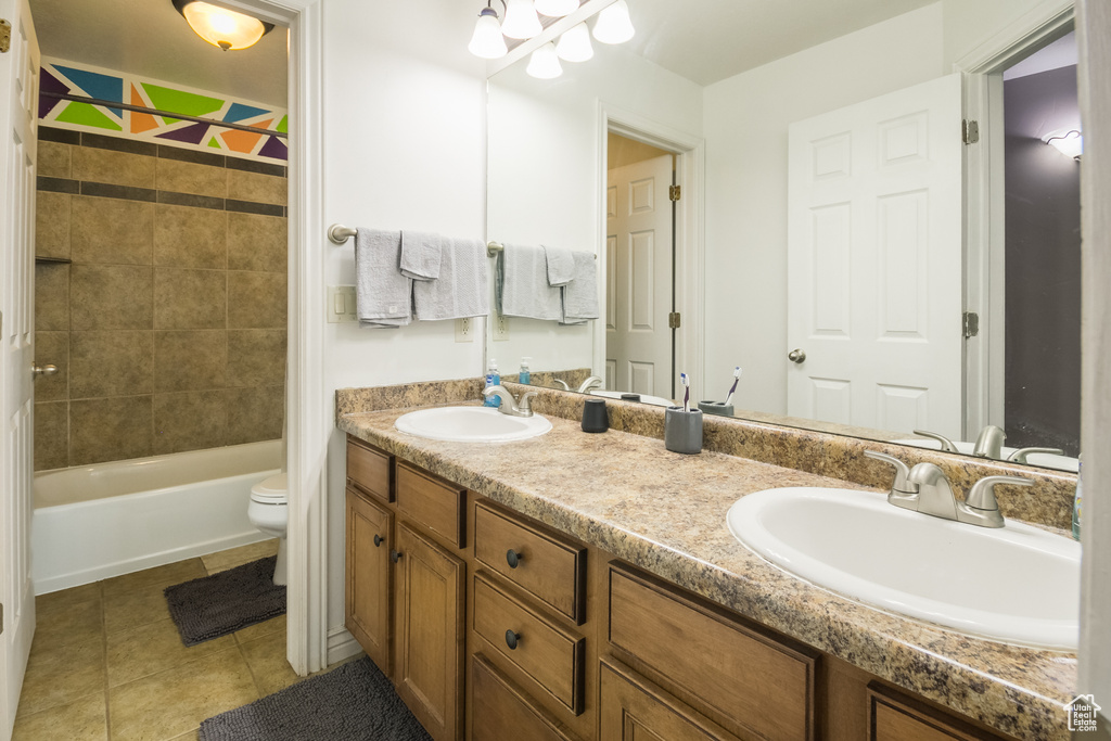 Bathroom featuring double vanity, toilet, tile patterned flooring, bathtub / shower combination, and a chandelier