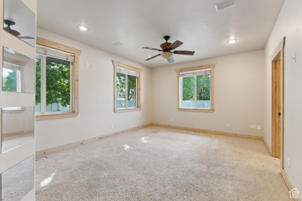 Carpeted spare room featuring plenty of natural light, ceiling fan, recessed lighting, and baseboards
