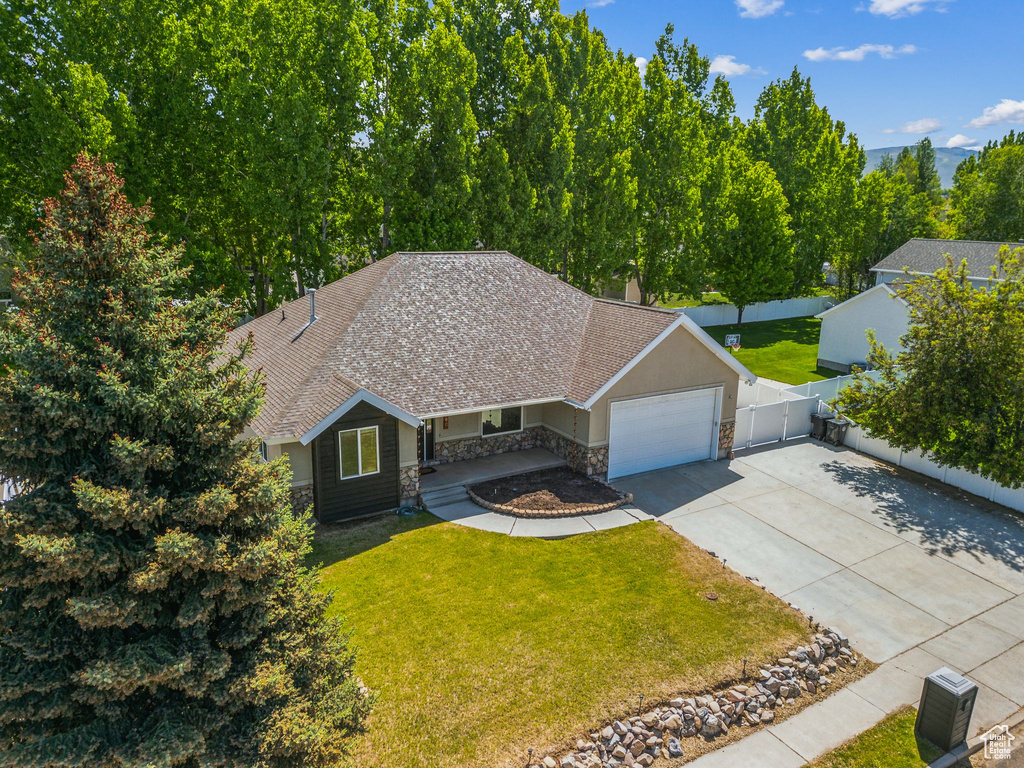 View of front of property with stone siding, driveway, a garage, a shingled roof, and a chimney