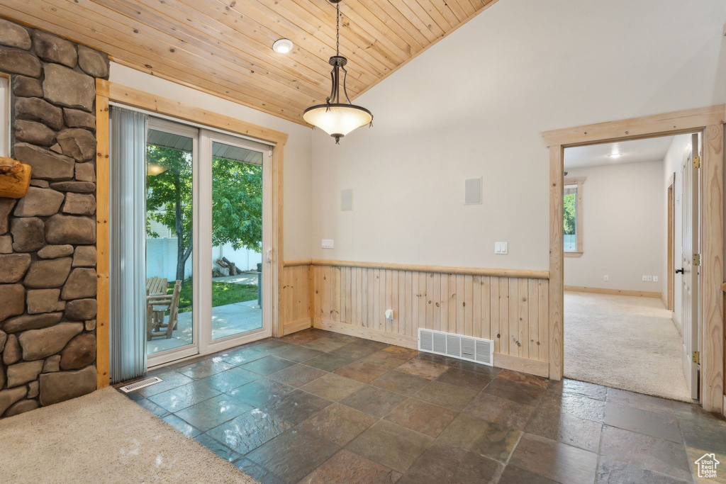 Spare room featuring wooden ceiling, stone tile flooring, wainscoting, lofted ceiling, and baseboards
