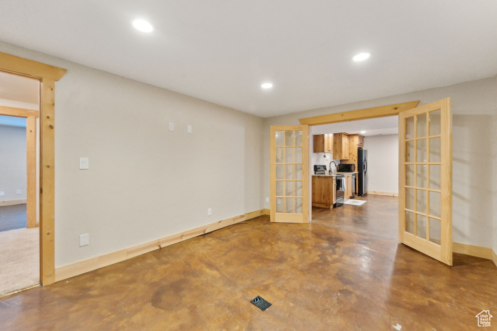Unfurnished living room featuring french doors, finished concrete floors, recessed lighting, and baseboards