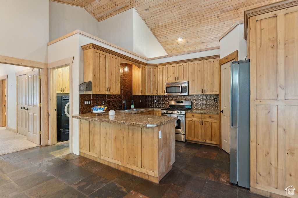 Kitchen with appliances with stainless steel finishes, a sink, a peninsula, high vaulted ceiling, and wooden ceiling