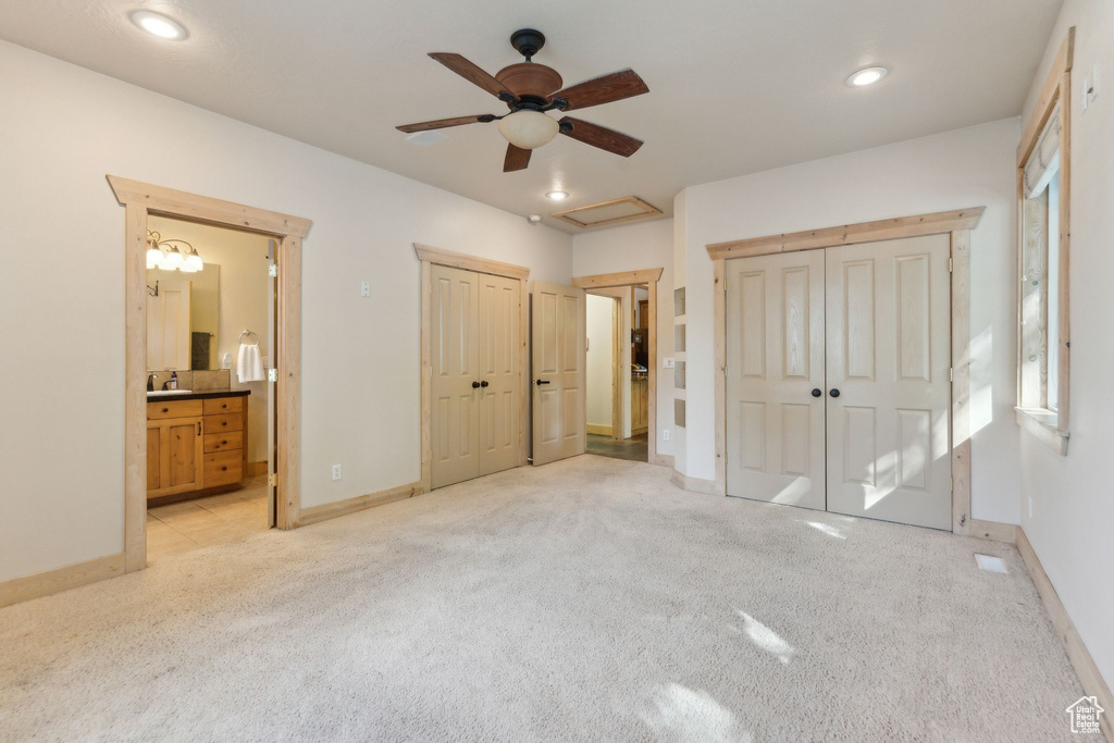 Unfurnished bedroom featuring light colored carpet, baseboards, multiple closets, ensuite bath, and recessed lighting