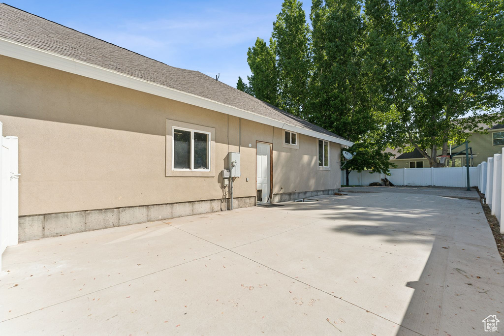 View of property exterior featuring a shingled roof and a patio