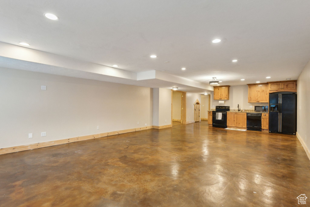 Unfurnished living room featuring recessed lighting, a sink, baseboards, and finished concrete flooring