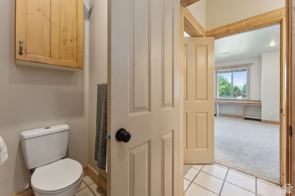 Bathroom featuring toilet, tile patterned flooring, and baseboards
