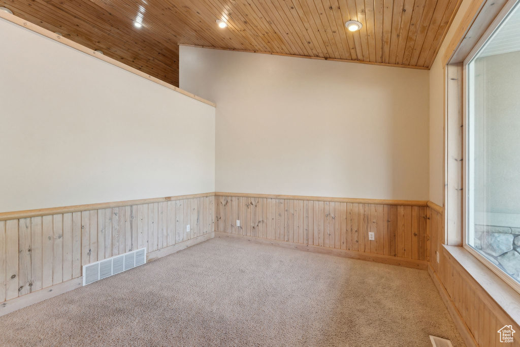 Carpeted spare room with wainscoting, recessed lighting, wood ceiling, and wooden walls