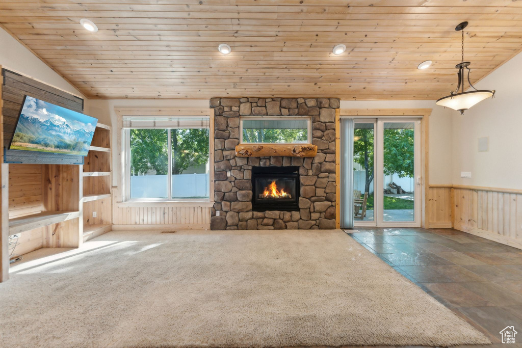 Unfurnished living room with wooden ceiling, healthy amount of natural light, a stone fireplace, wainscoting, and recessed lighting