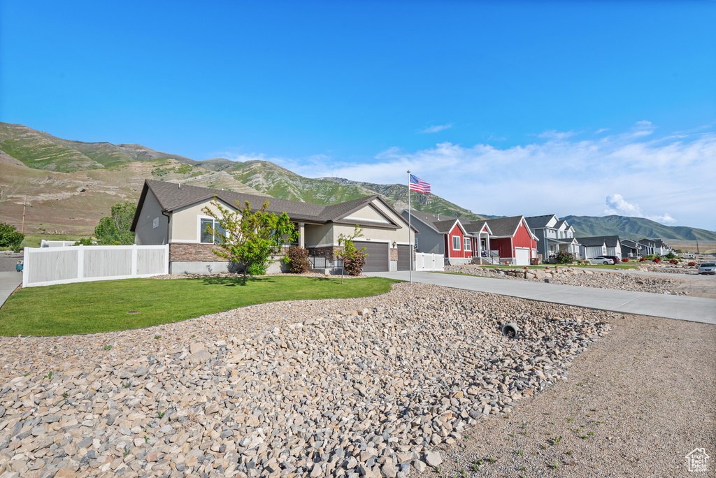 Ranch-style house featuring a mountain view, concrete driveway, an attached garage, and a residential view