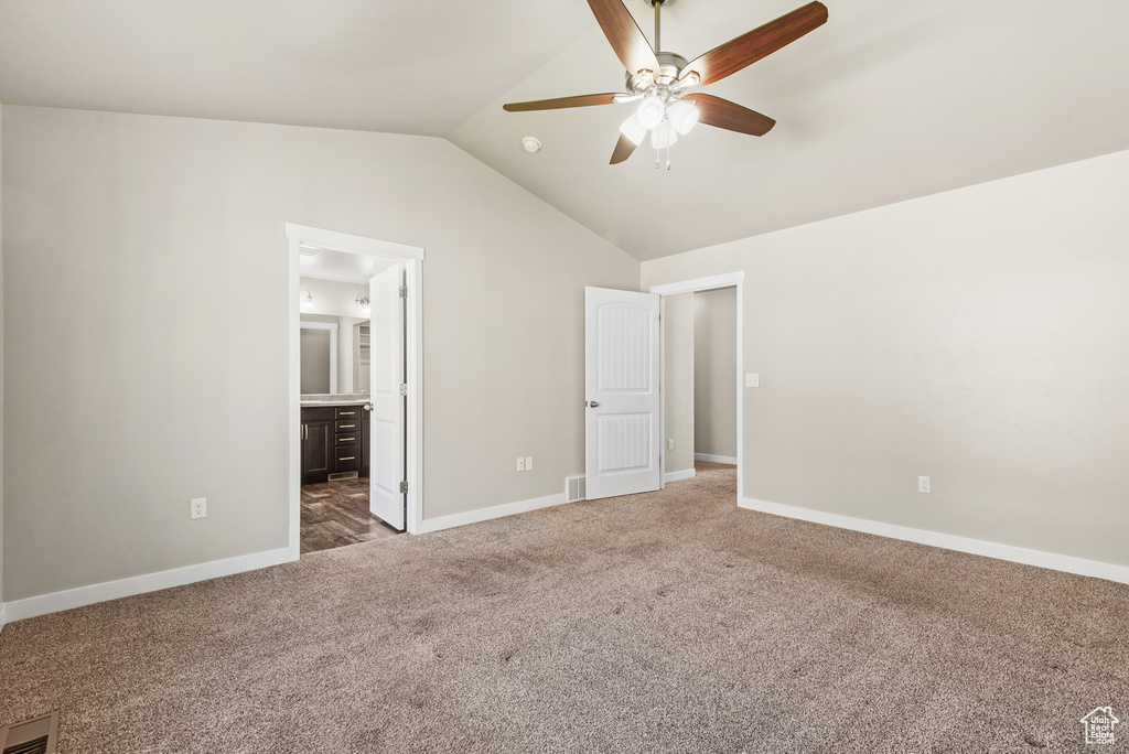 Unfurnished bedroom with carpet, vaulted ceiling, baseboards, ensuite bathroom, and a ceiling fan