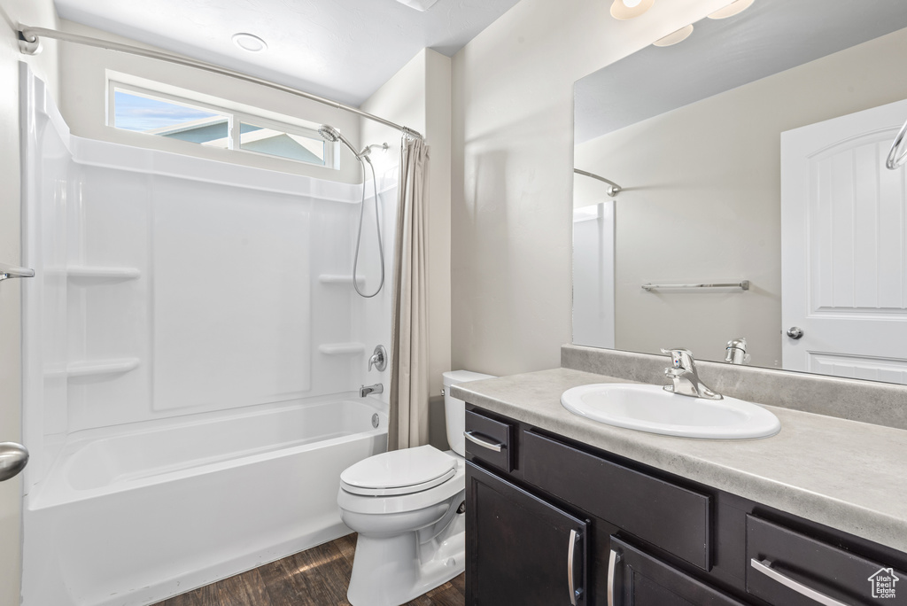 Bathroom featuring vanity, shower / bath combo with shower curtain, wood finished floors, and toilet