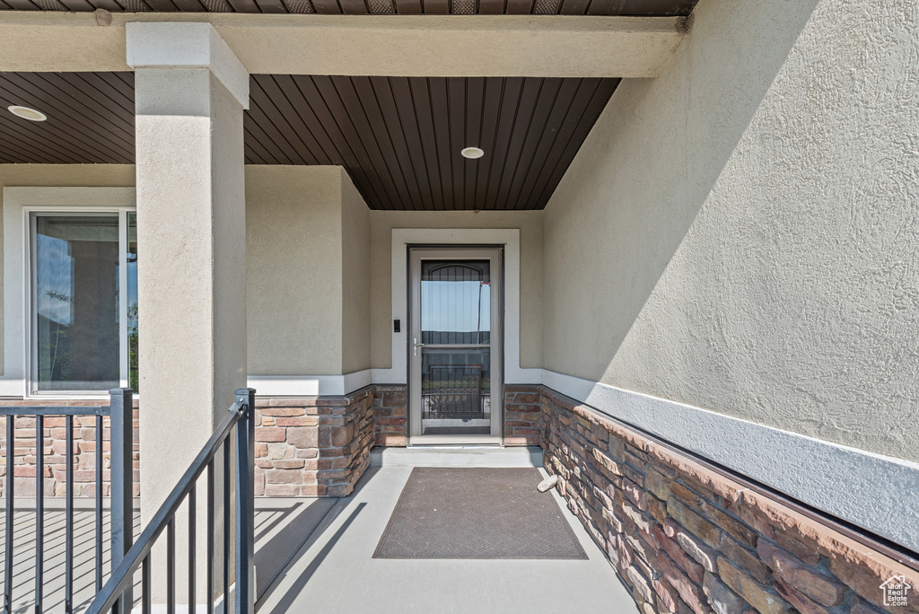 Doorway to property featuring stucco siding and stone siding