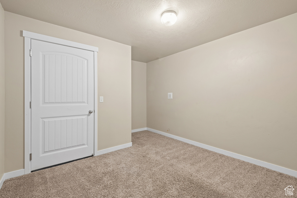 Unfurnished bedroom with light carpet, baseboards, and a textured ceiling