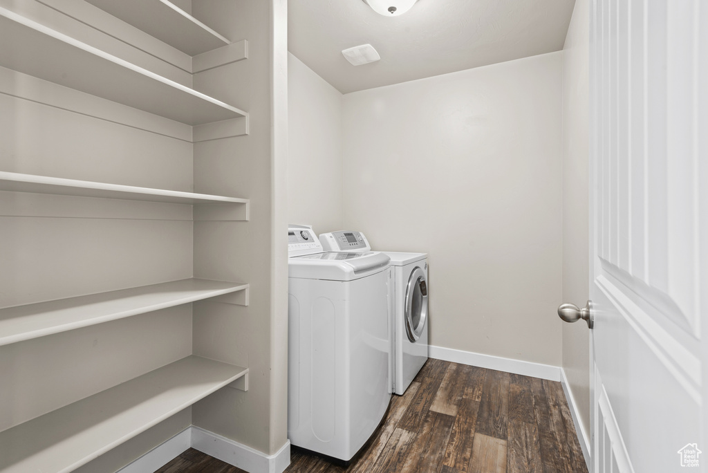 Washroom featuring washer and clothes dryer, dark wood-style flooring, and baseboards