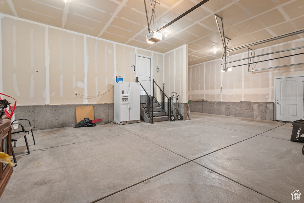 Garage with white fridge with ice dispenser and a garage door opener