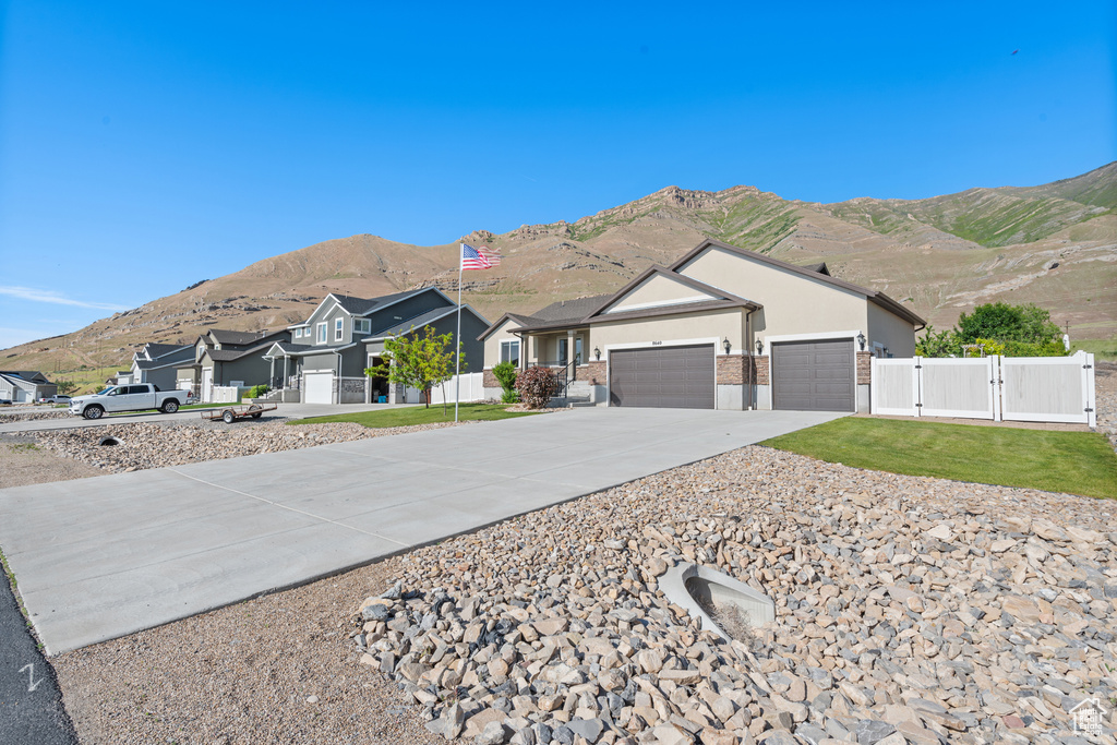 Single story home with a gate, concrete driveway, a garage, a mountain view, and a residential view