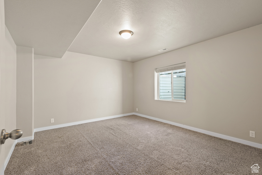 Unfurnished room featuring carpet floors, baseboards, and a textured ceiling
