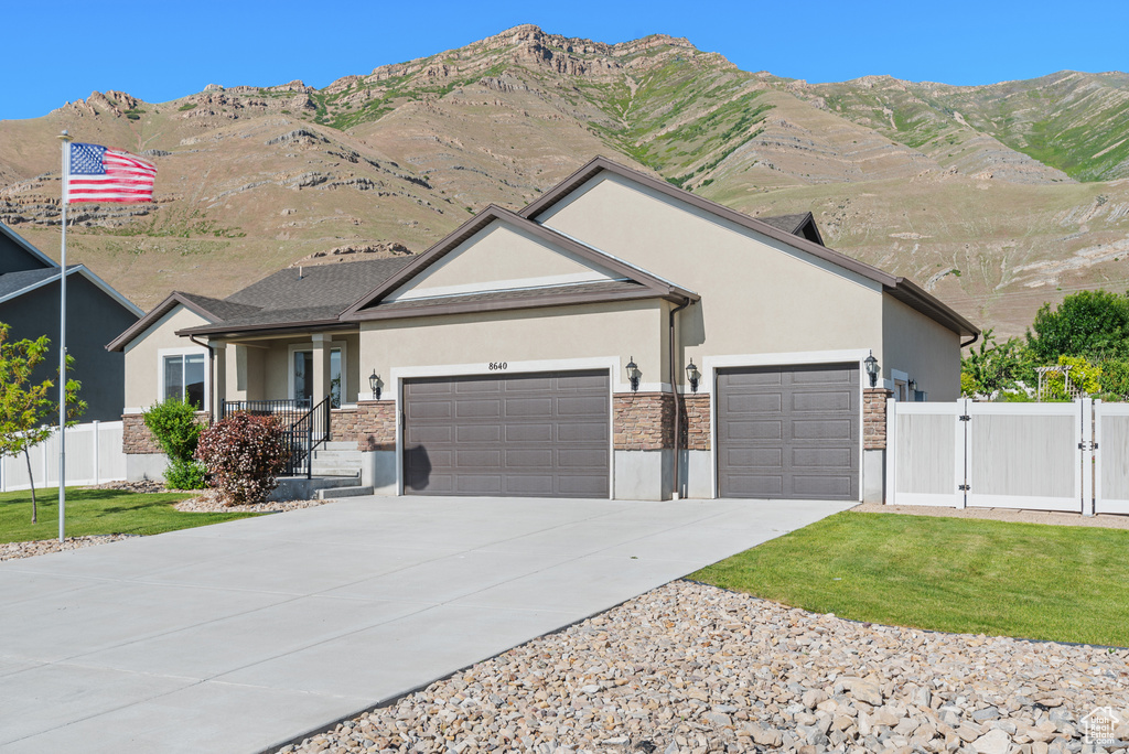 Ranch-style house with stucco siding, a garage, a gate, and stone siding
