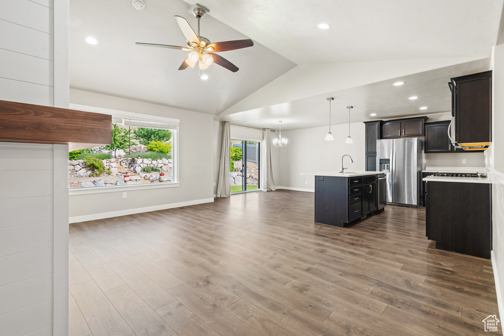 Unfurnished living room featuring a sink, ceiling fan, lofted ceiling, dark wood-type flooring, and a chandelier