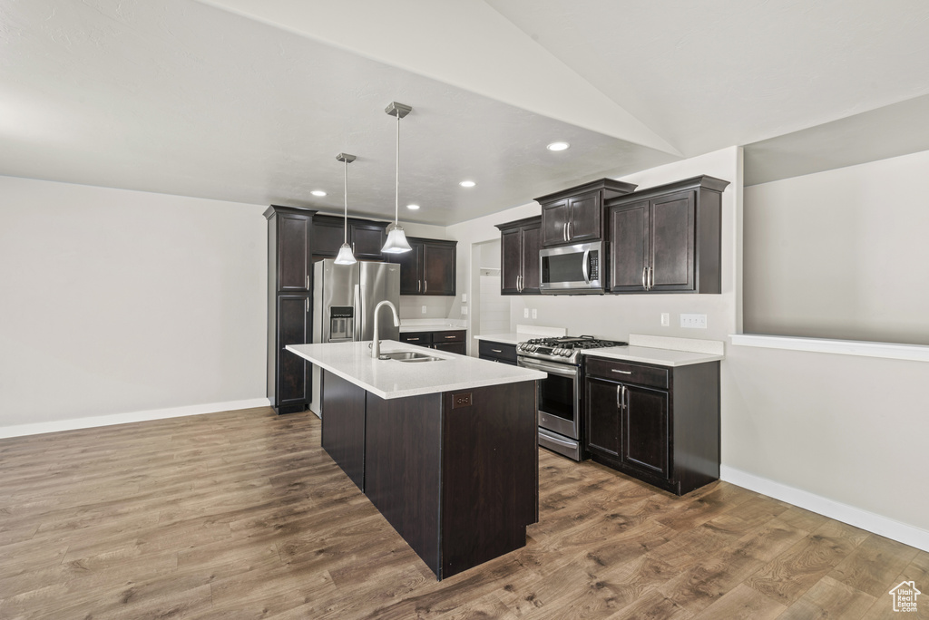 Kitchen featuring stainless steel appliances, a sink, light countertops, recessed lighting, and wood finished floors